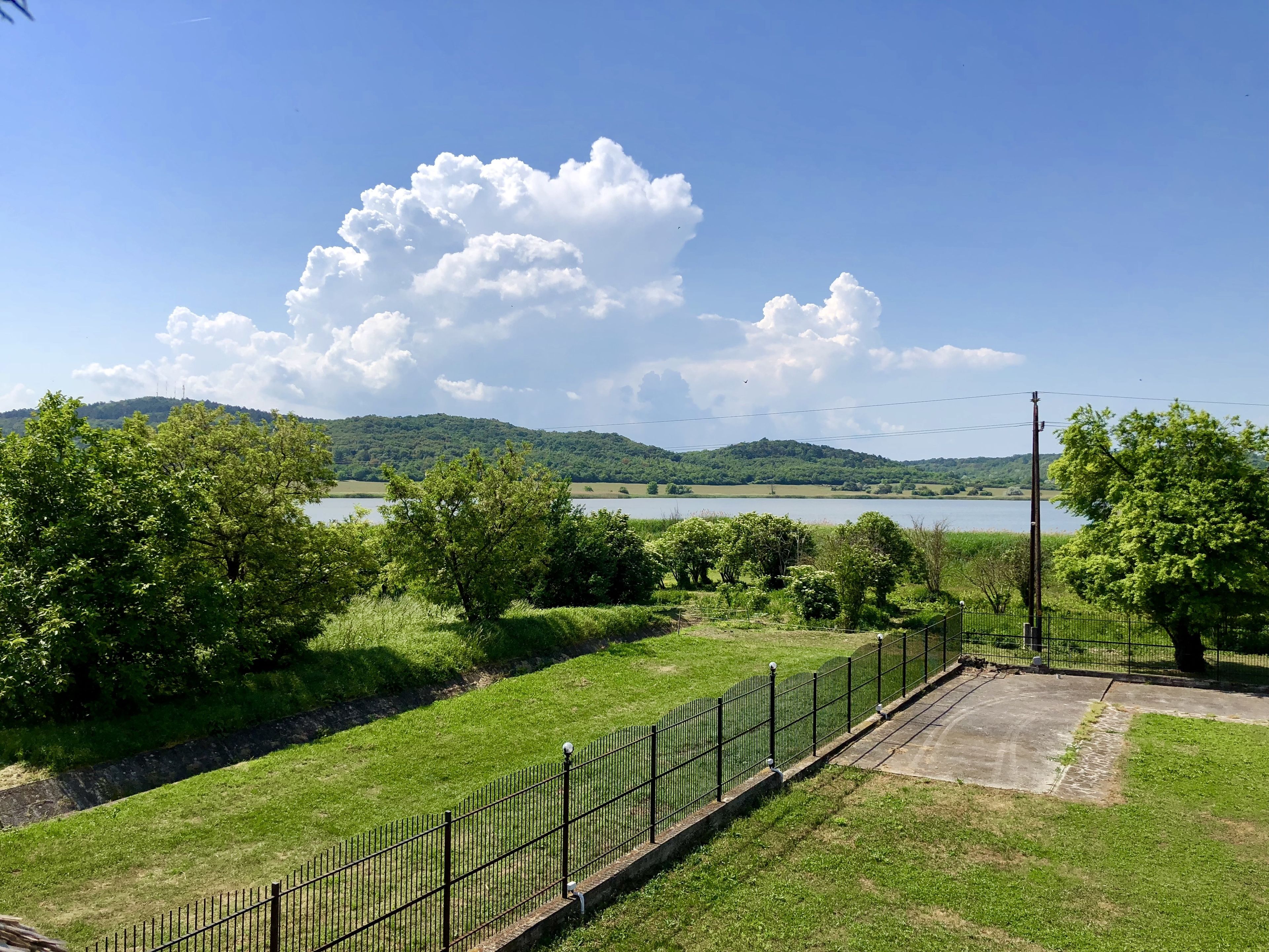 A fenced park area with a lake and hills in the background.
