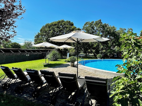 Una piscina al aire libre de temporada, sombrillas. The Houses of History - anno 1830