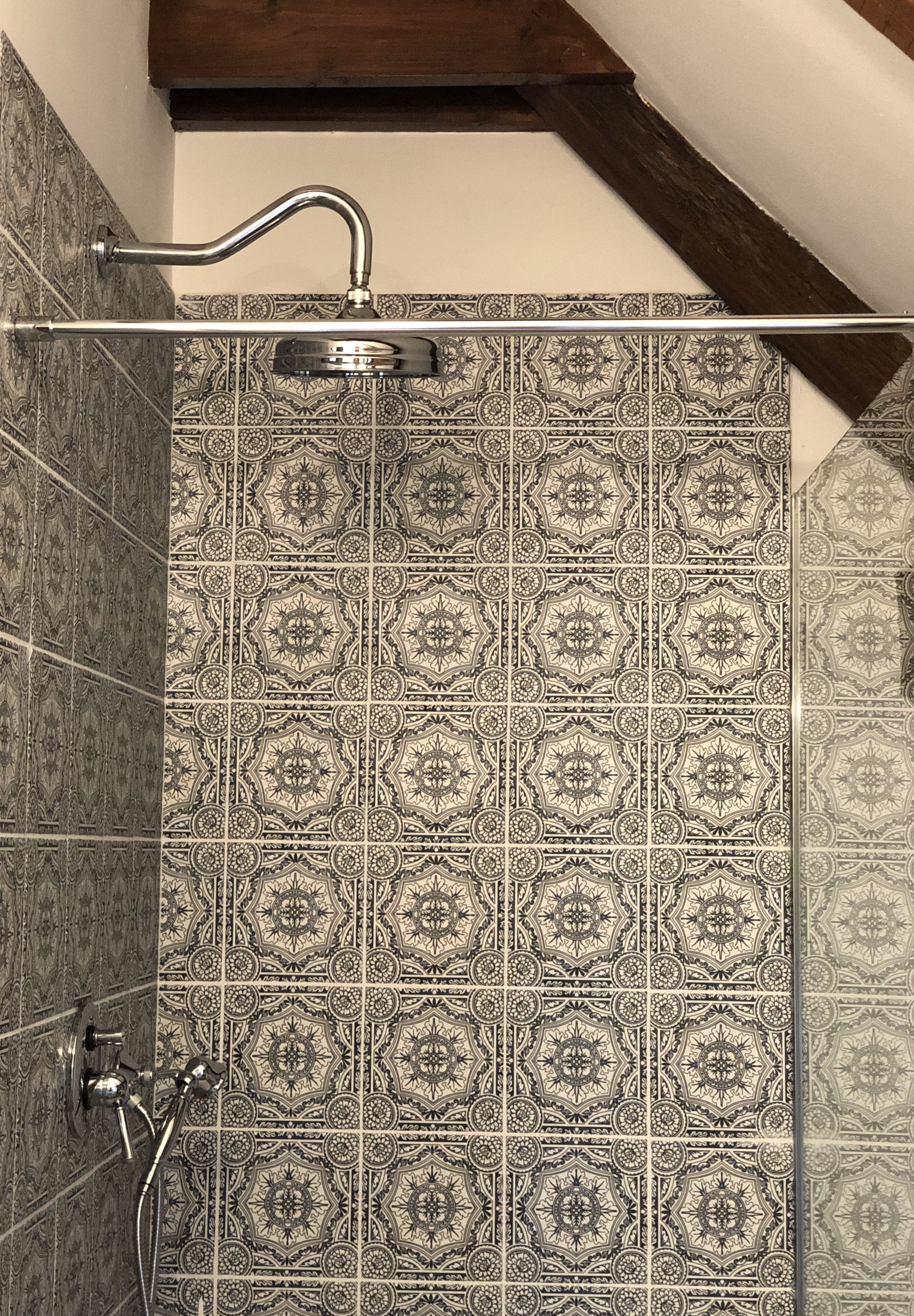 A shower area with patterned tiles and a metal showerhead.