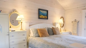A bedroom with a bed, two bedside tables with lamps, a dresser, and a mirror.