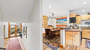 A modern kitchen with wooden cabinets, a dining area with a rug, and a staircase leading to a balcony. - Grand Hyatt| Private, tranquil condo with multi level living area and cozy fireplace (Vail)