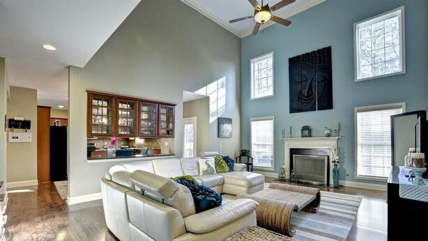 A spacious living room with a large white sofa, a fireplace, and a ceiling fan.