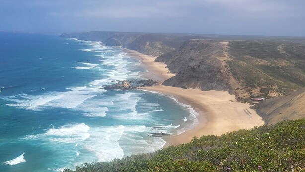 Un paisaje costero con playa, acantilados y olas del océano.