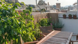 A rooftop terrace with a wooden table and chairs, surrounded by potted plants and a bamboo fence. - Ariadne's Penthouse in Central Athens by JJ Hospitality (Athina)