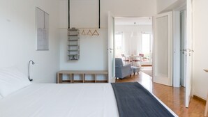 A bedroom with a large bed, a bedside table, a hanging shelf, and a view into a dining area. - Ariadne's Penthouse in Central Athens by JJ Hospitality (Athina)