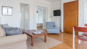 A living room with a sofa, a coffee table, a blue armchair, and a wooden door. - Ariadne's Penthouse in Central Athens by JJ Hospitality (Athina)