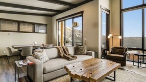 A modern living room with a sofa, coffee table, and a dining area. - Schweitzer Luxury Ski in/out Townhome | Hot Tub (Sandpoint)
