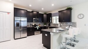 A modern kitchen with dark cabinetry, stainless steel appliances, and a granite countertop.