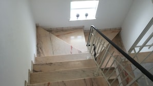 A marble staircase with a metal railing, leading to a landing with a small window. - Villa in Algarve with complete privacy (moncarapacho,)