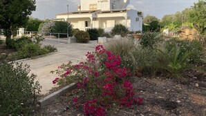A two-story house with a balcony, surrounded by a garden with various plants and flowers. - Villa in Algarve with complete privacy (moncarapacho,)
