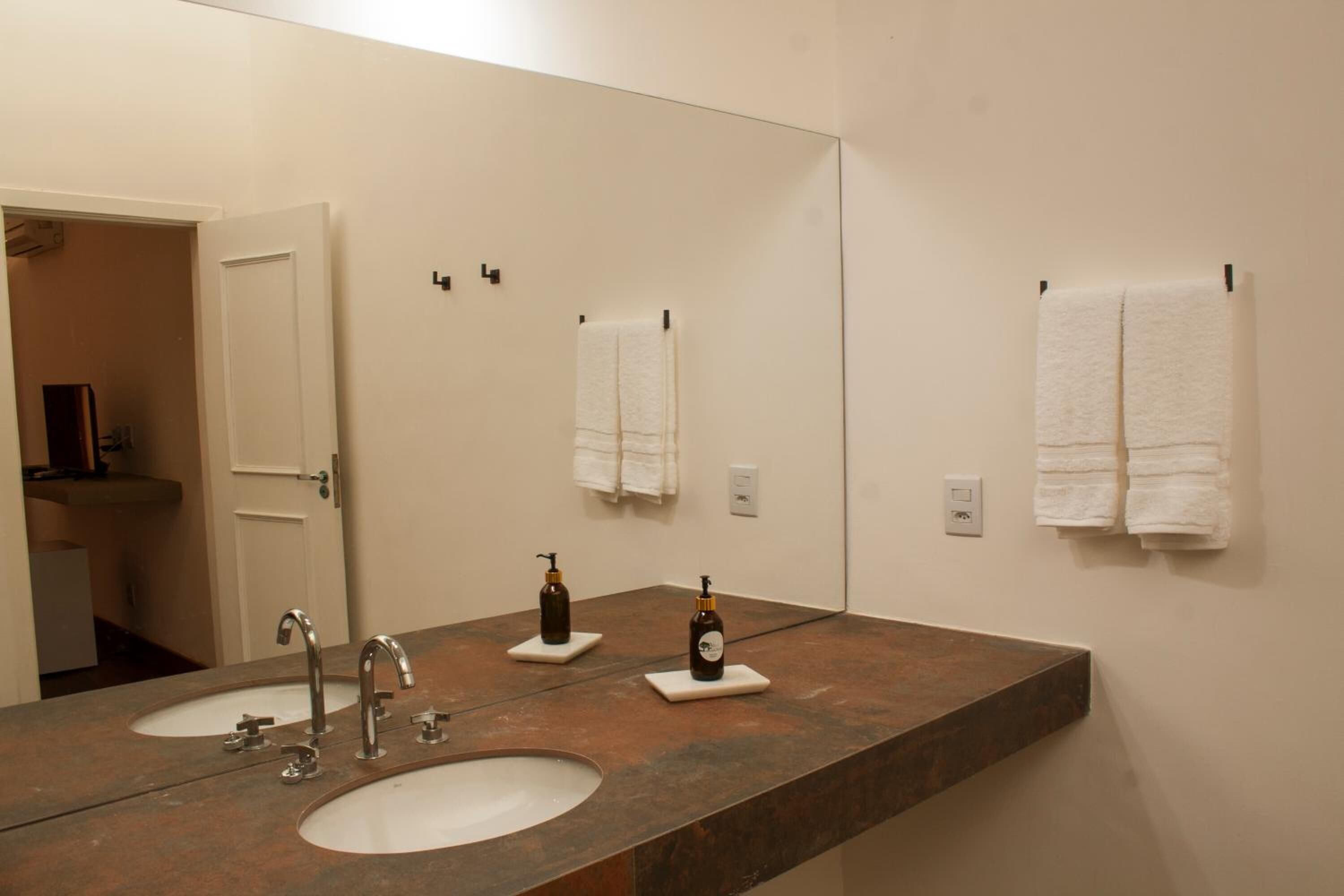 A bathroom with two sinks, a large mirror, and two bottles of soap on the counter.