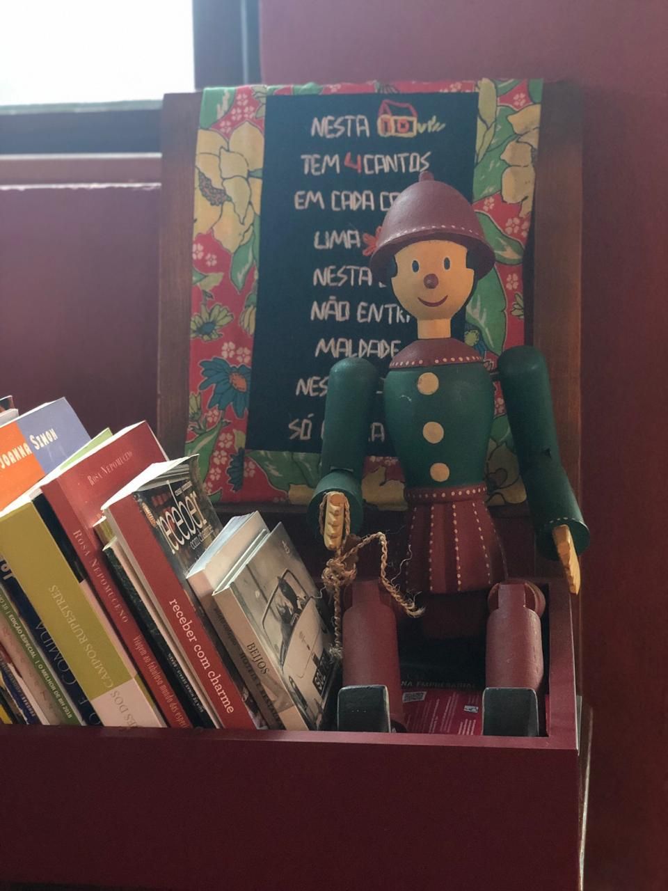 Uma estante com livros e uma pequena figura de madeira.