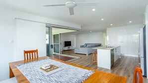 A modern apartment with a dining area, kitchen, and living space. - 25 Cooloola Drive - Rainbow Beach. Stunning, Modern, Open Plan Beach House. Wifi. (RAINBOW BEACH)