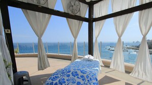 Une chambre avec un lit, des rideaux blancs et une vue sur la mer.