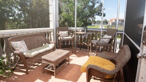 Un patio couvert aménagé avec des meubles en osier, notamment un canapé, des fauteuils et une table.