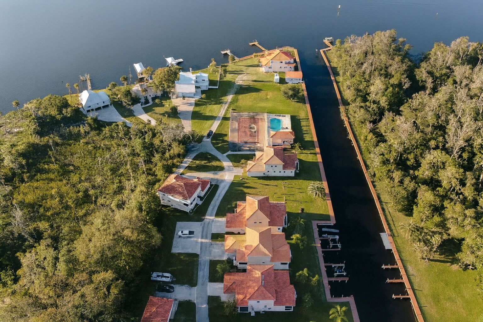 An aerial view of a residential area with houses, a swimming pool, and a dock.