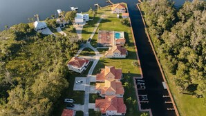 Vue aérienne d’un quartier résidentiel avec des maisons, une piscine et un quai.