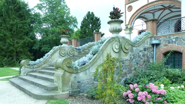 A stone staircase leading up to a building with a brick facade and an arched entrance.