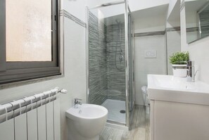 Een moderne badkamer met een douchecabine van glas, een wit wastafelmeubel en een grote spiegel.