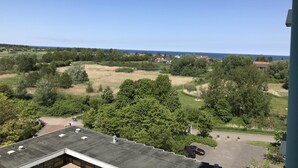 A view from a high vantage point overlooking a residential area with houses, trees, and a body of water. - This 30 m&sup2; vacation apartment (west-facing) is located on the 6th floor of the Kiel building. A double bed and two sleeper chairs can accommodate up to 4 people. . <br><br>The built-in kitchen is fully equipped for self-catering. The cozy one. (Schönberg OT Holm)