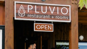 A wooden building with a sign reading "PLUVIO restaurant + rooms OPEN." - Pluvio Restaurant and Rooms (Ucluelet)