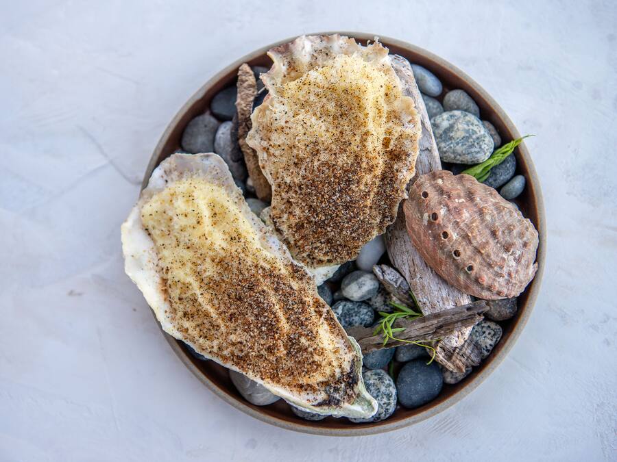 Three scallops on a bed of pebbles and seaweed.