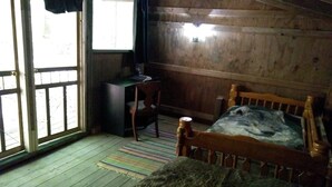 A wooden cabin room with a bed, a desk, and a chair. - Coyote's Den Rustic Cabin  for Adventurous Camper (Freeville)