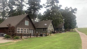 Een rij tweelaagse huizen met een houten gevel, een omheinde tuin en een pad dat naar de huizen leidt.