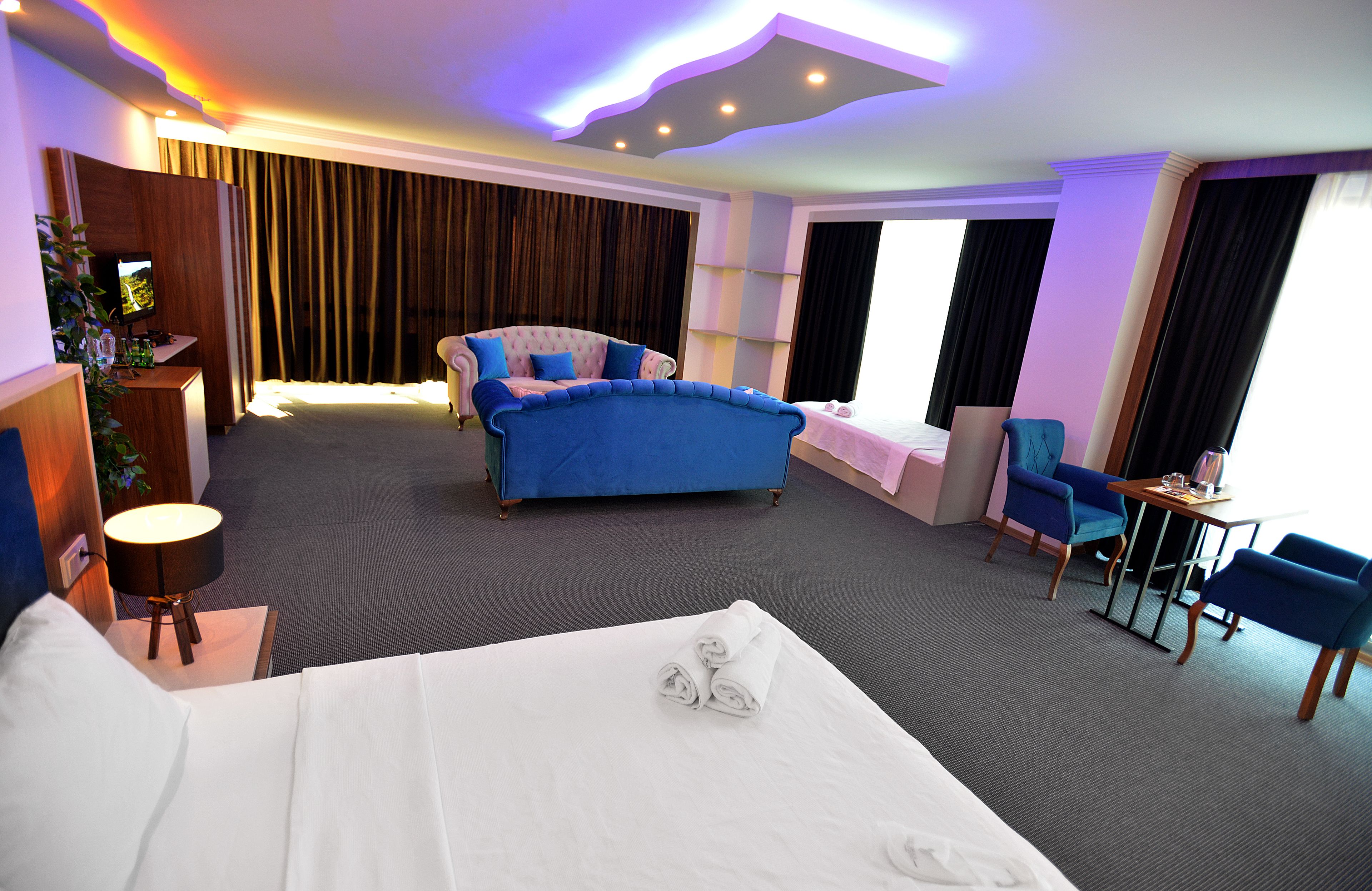 Hotellihuone, jossa on suuri sänky, sohva, työpöytä ja tuoli.