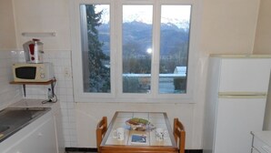 Una cocina con una mesa de comedor, sillas, microondas y refrigerador.