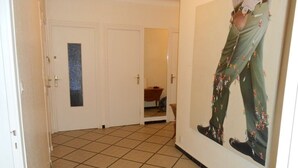 Un pasillo con piso de baldosas, puertas blancas y una obra de arte grande colgada en la pared.