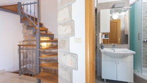 A staircase with wooden steps and metal railings, leading to a bathroom with a white sink and a mirror above it. - Holiday house Layla in Tucepi, sea view (Tucepi)