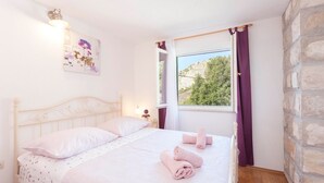A bedroom with a bed, a window with curtains, a wall-mounted light, and a painting. - Holiday house Layla in Tucepi, sea view (Tucepi)