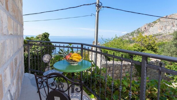 A balcony with a table holding a bowl of fruit, overlooking a mountainous landscape. - Holiday house Layla in Tucepi, sea view (Tucepi)