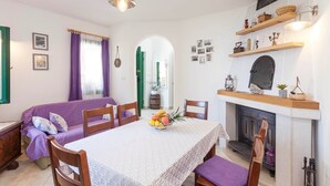 A dining area with a table set for four, a fireplace, and a green archway leading to another room. - Holiday house Layla in Tucepi, sea view (Tucepi)