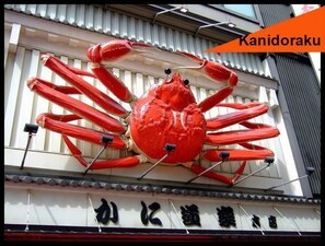 A large red crab sculpture mounted on a building facade. - City central studio Apartments (Osaka)
