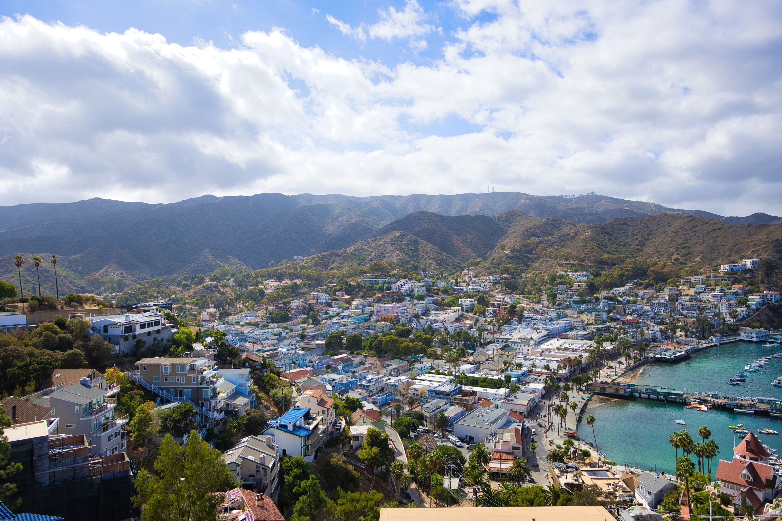 Une ville côtière dotée d’un port de plaisance, entourée de collines et de montagnes.