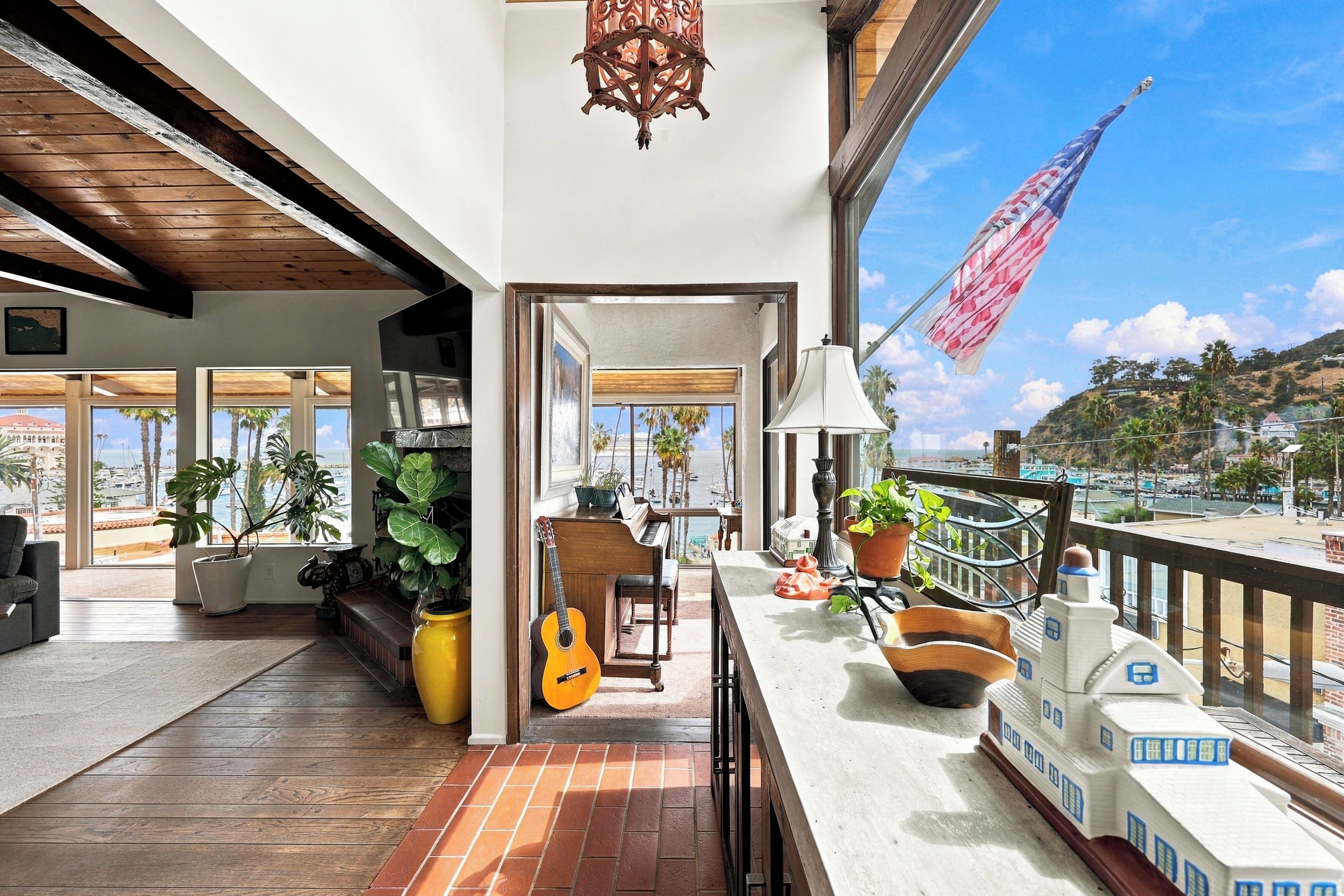A balcony with a piano, a guitar, potted plants, and a flag.