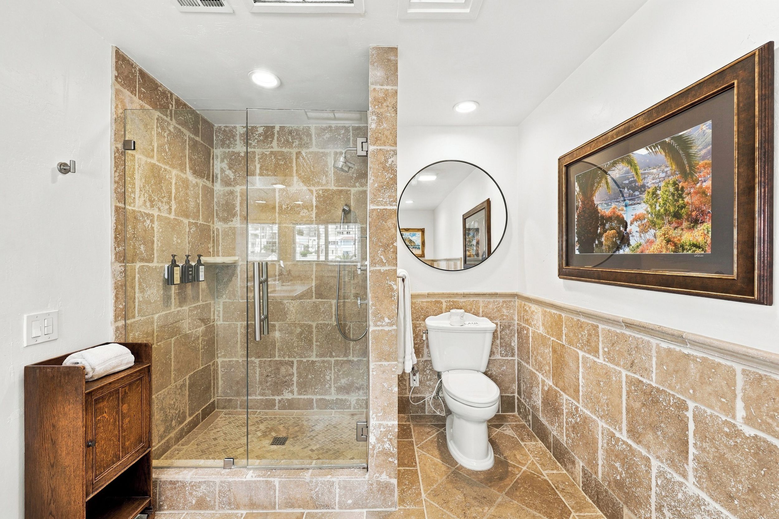 Une salle de bain avec une douche à parois de verre, des toilettes et un meuble en bois.