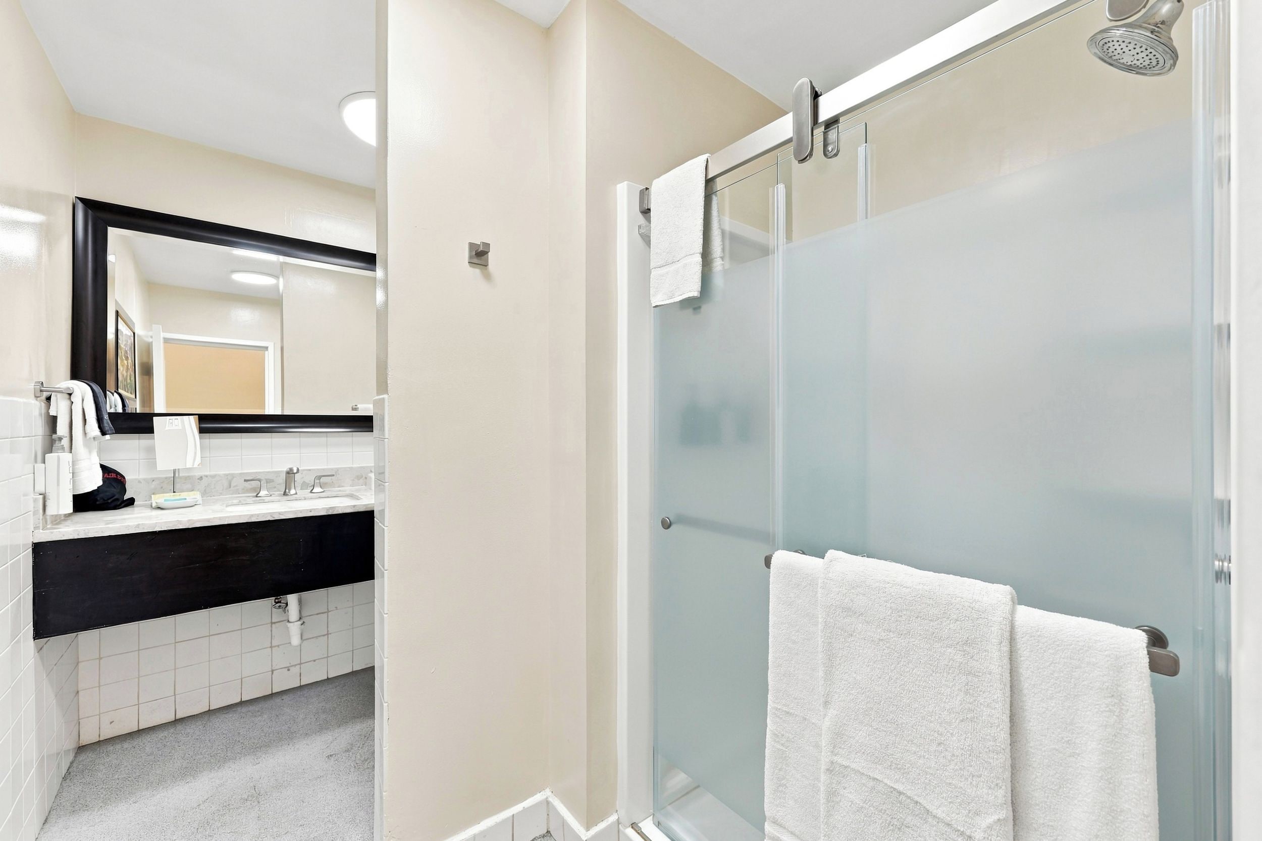 A modern bathroom with a glass shower enclosure, a sink with a black countertop, and a mirror above the sink.