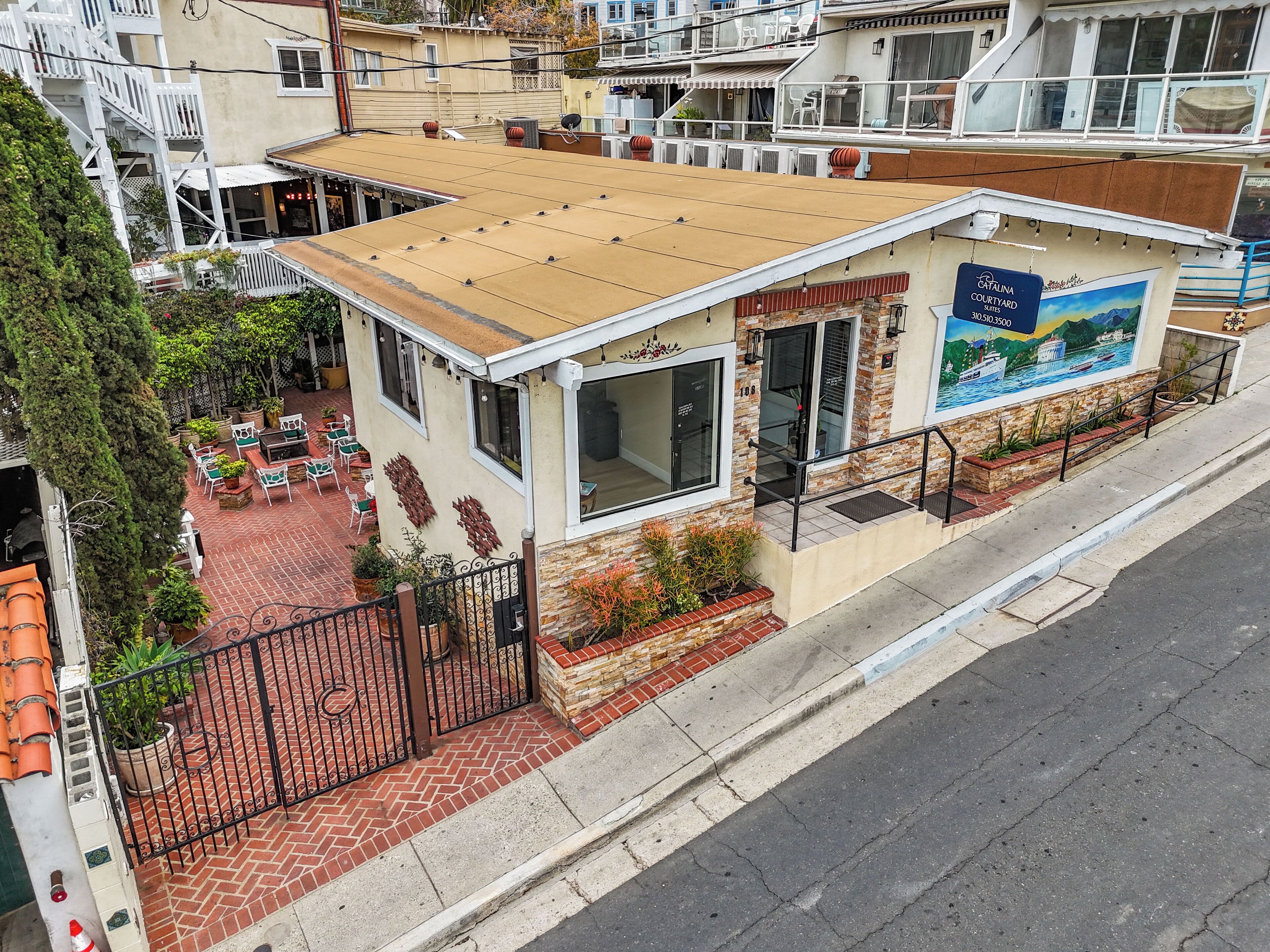 Un bâtiment doté d’un patio, d’une enseigne indiquant « Catalina Courtyard » et d’une fresque représentant un paysage côtier.