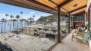 A balcony with a view of a marina, palm trees, and buildings. - Catalina Courtyard Suites (Avalon)