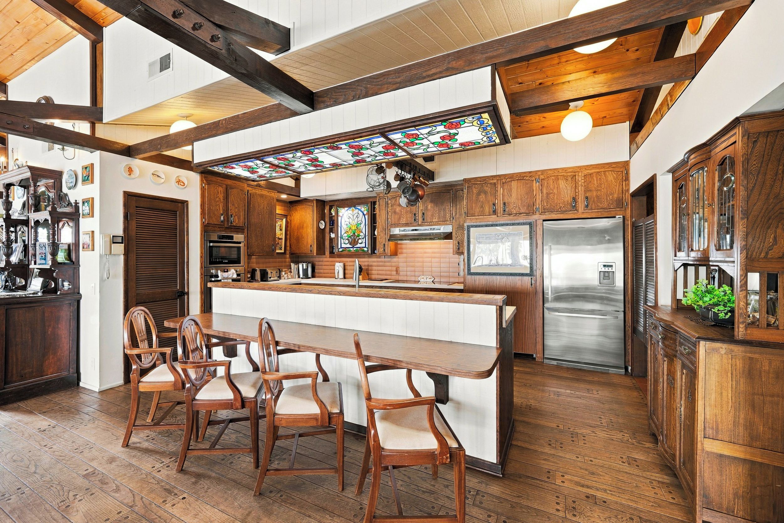 A kitchen with wooden cabinets, a large island, and a stainless steel refrigerator.