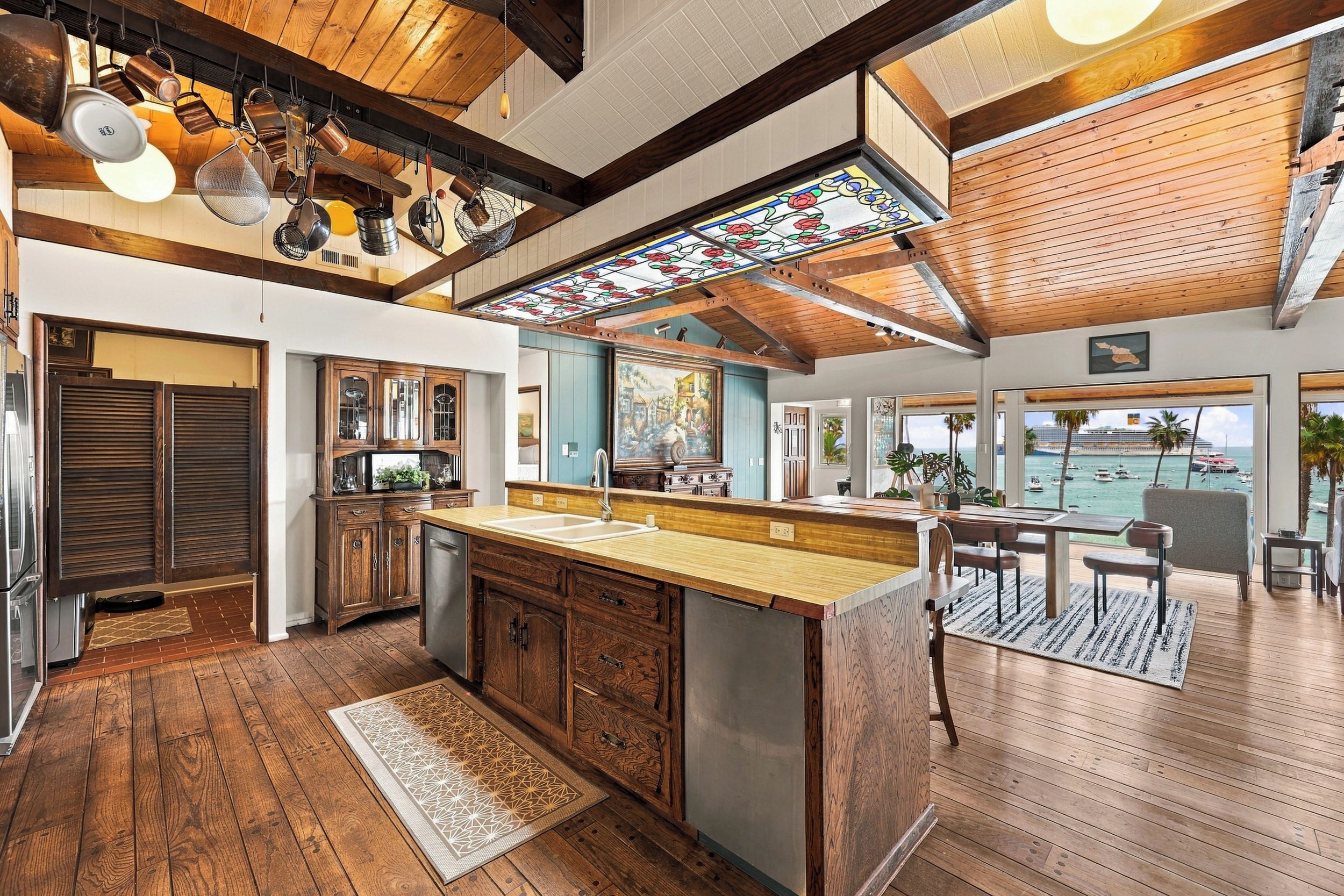 A spacious kitchen with wooden cabinets, a large island, and a view of the ocean through the windows.