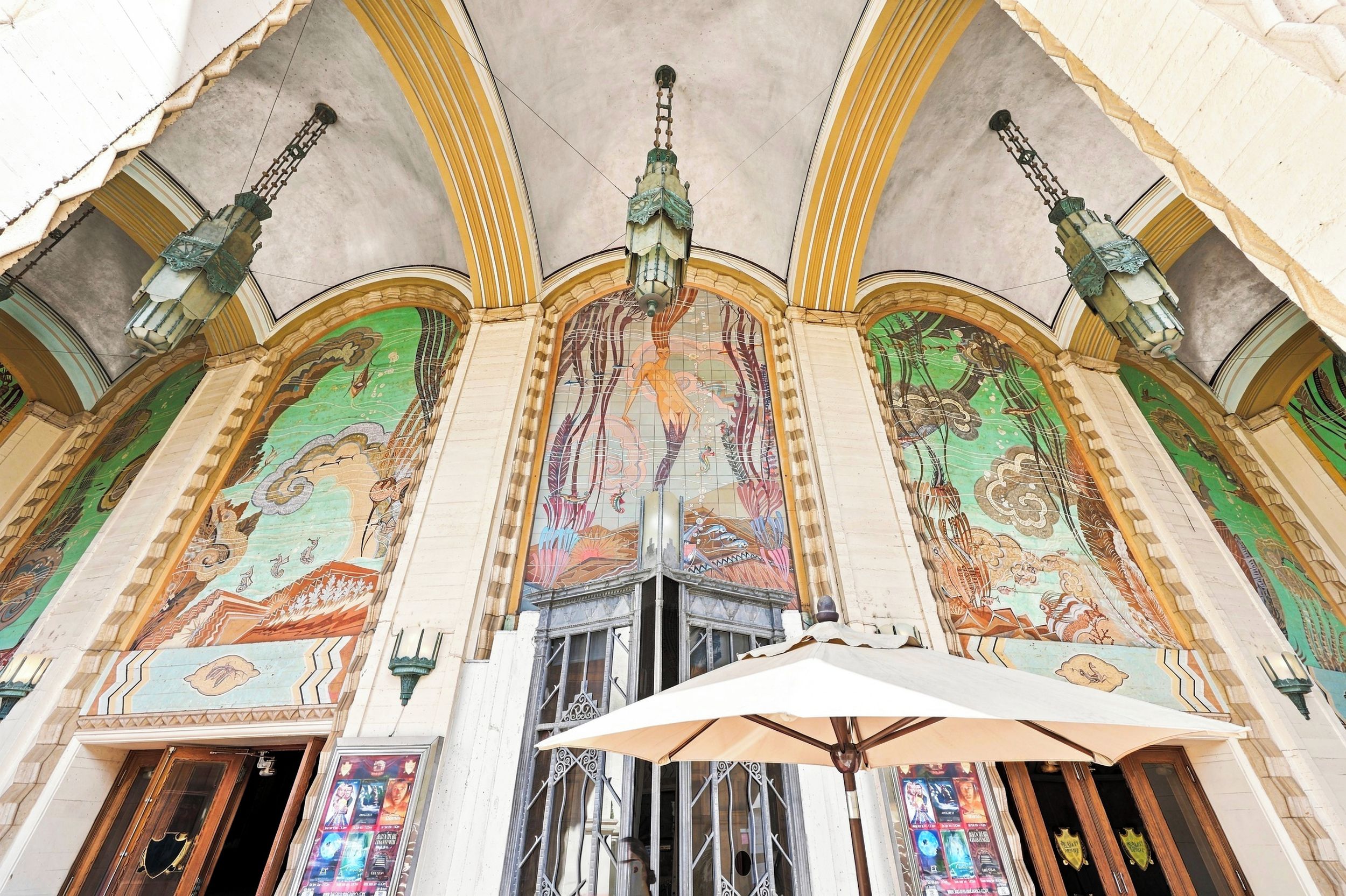 Un interior ornamentado con un gran techo abovedado, detallados trabajos en mosaico y una lámpara central.
