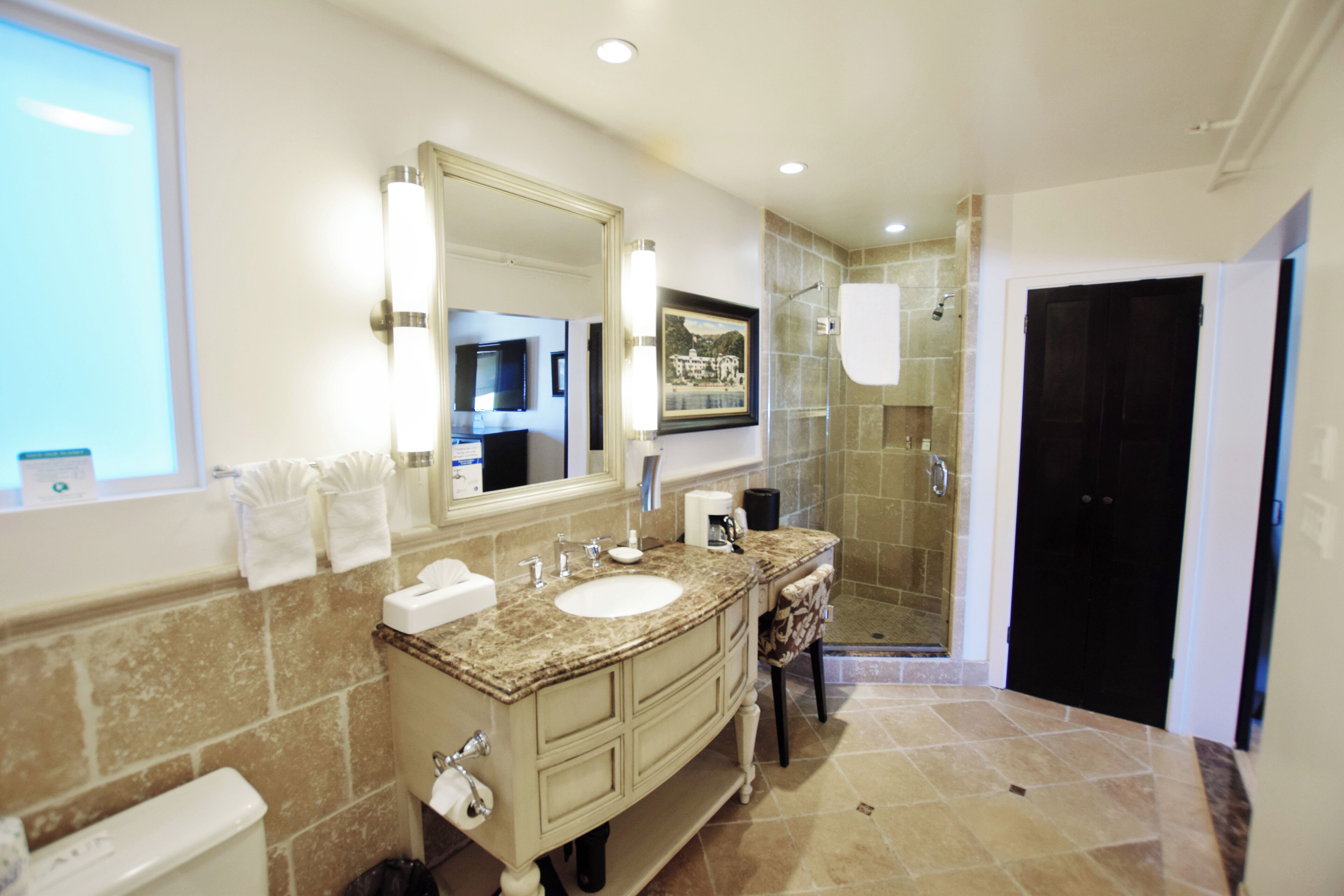 A modern bathroom with a large sink, vanity, and a walk-in shower.
