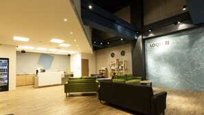 A modern lobby with a reception desk, green sofas, and a large wall with a map design. - iNN Hotel (Taichung)