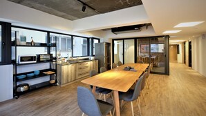A modern kitchen with a wooden table and chairs, a microwave, and a refrigerator. - iNN Hotel (Taichung)