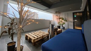 A modern room with a large window, a wooden pallet table, a blue sofa, and a potted plant. - iNN Hotel (Taichung)