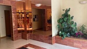 Moderni aula, jossa on lasiseinä, suuri ruukussa oleva kasvi ja vastaanottotiski.
